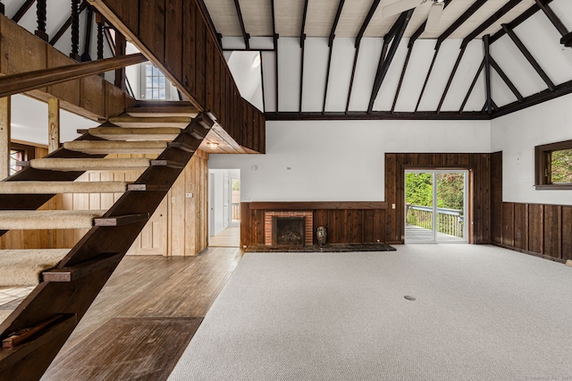 302 Ferry Rd, Old Lyme, CT 06371 - unfurnished living room featuring high vaulted ceiling, a fireplace, a wainscoted wall, wooden walls, and stairs