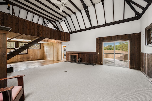 302 Ferry Rd, Old Lyme, CT 06371 - unfurnished living room featuring high vaulted ceiling, carpet, wooden walls, a brick fireplace, and a wainscoted wall