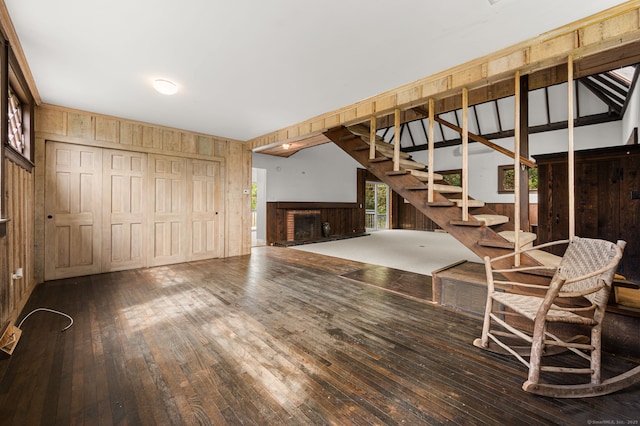 302 Ferry Rd, Old Lyme, CT 06371 - unfurnished living room with wood walls, a brick fireplace, wood-type flooring, and stairs