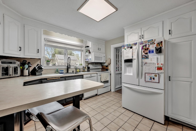 kitchen with visible vents, a sink, white cabinets, and white appliances