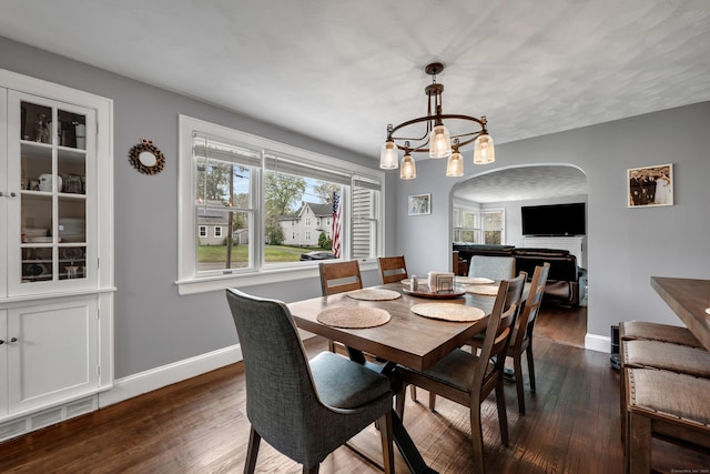 dining area featuring visible vents, arched walkways, dark wood finished floors, baseboards, and an inviting chandelier