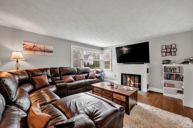 living room with baseboards, wood-type flooring, and a brick fireplace