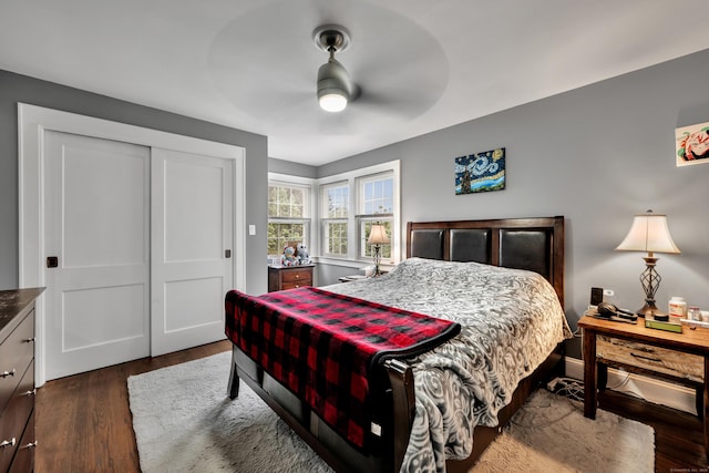 bedroom with dark wood-type flooring, a ceiling fan, and a closet