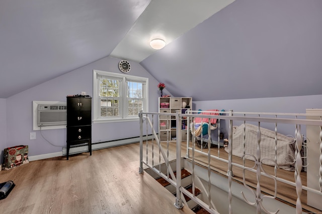 interior space featuring a wall mounted air conditioner, a baseboard heating unit, baseboards, vaulted ceiling, and wood finished floors