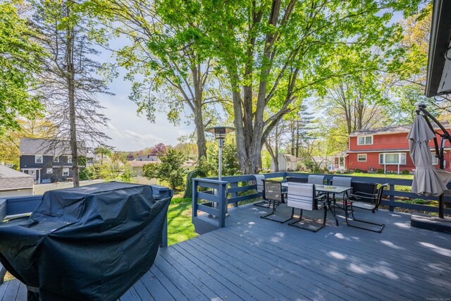 wooden deck featuring outdoor dining area, a grill, and a residential view