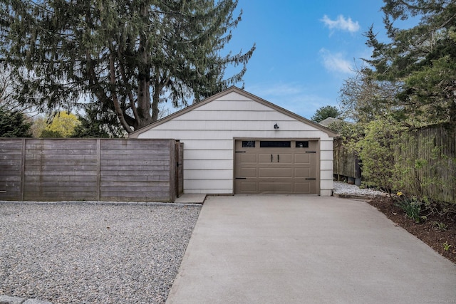 detached garage featuring fence and driveway