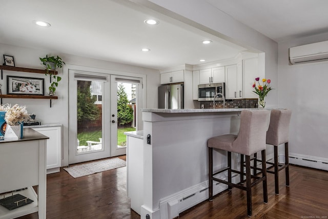 kitchen featuring white cabinets, appliances with stainless steel finishes, a breakfast bar, decorative backsplash, and a wall unit AC