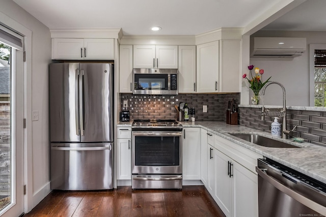 kitchen featuring stainless steel appliances, a wall unit AC, a sink, and plenty of natural light