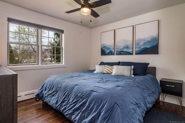 bedroom with ceiling fan, a baseboard heating unit, and wood finished floors