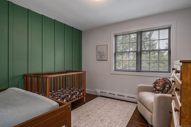 bedroom with dark wood-style flooring, baseboards, and a baseboard radiator