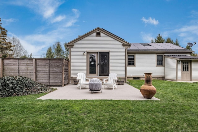 back of property featuring a patio area, fence, a yard, and solar panels
