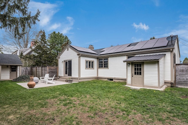 rear view of house with a lawn, fence, a patio, and solar panels