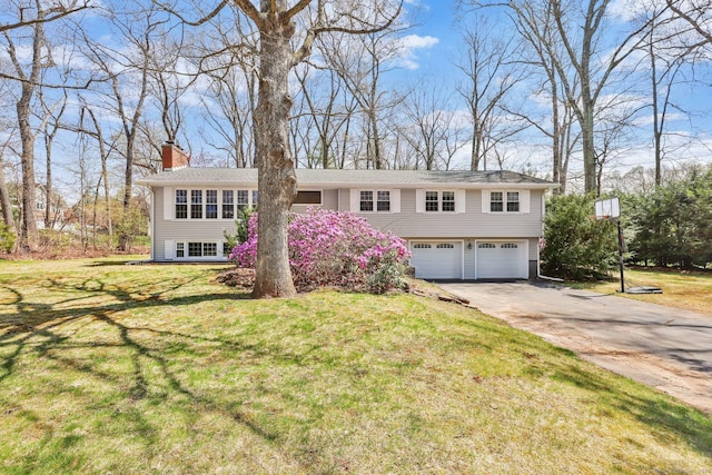 view of front of property featuring an attached garage, a front yard, driveway, and a chimney