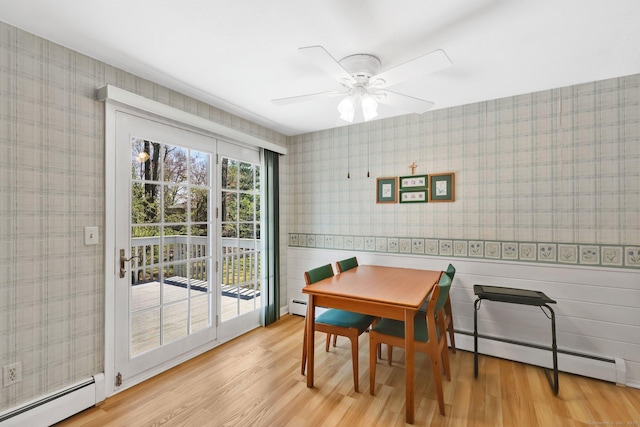 dining area featuring wood finished floors, baseboard heating, and wallpapered walls