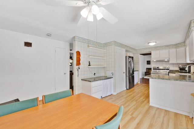 kitchen featuring under cabinet range hood, dark countertops, appliances with stainless steel finishes, and a sink