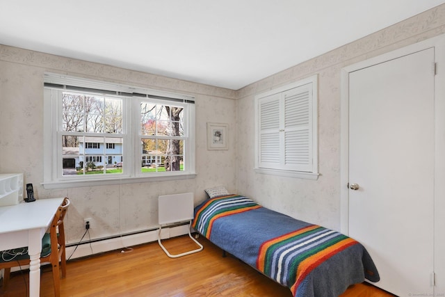 bedroom with wallpapered walls, light wood finished floors, and a baseboard radiator