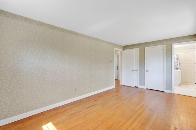 unfurnished bedroom featuring light wood-type flooring and ensuite bath