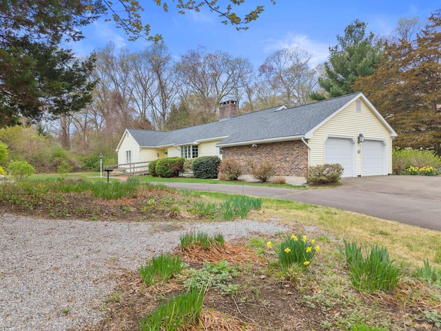 view of front of property featuring driveway, a chimney, roof with shingles, brick siding, and an attached garage