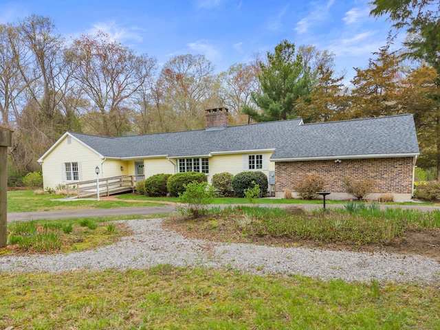 single story home featuring brick siding, roof with shingles, a chimney, and a deck
