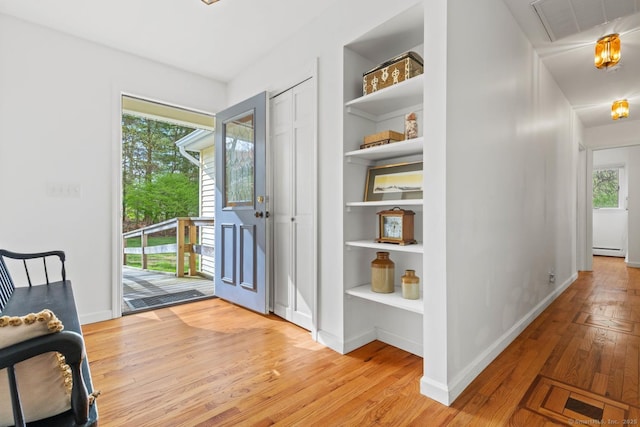interior space with visible vents, built in features, baseboard heating, baseboards, and light wood finished floors