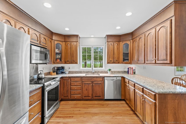 kitchen featuring brown cabinets, stainless steel appliances, a sink, and light wood-style floors