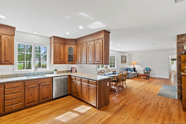 kitchen featuring a sink, brown cabinets, stainless steel dishwasher, and light wood-type flooring