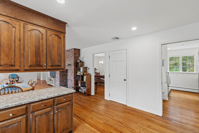 kitchen featuring light wood finished floors, brown cabinets, and baseboard heating