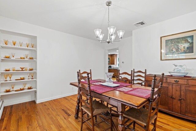 dining room with a notable chandelier, baseboard heating, light wood-style floors, baseboards, and visible vents