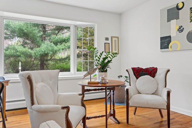 sitting room with baseboards, baseboard heating, and wood finished floors