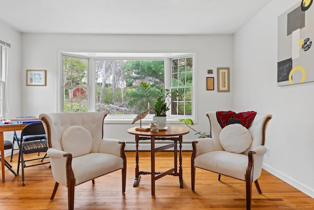 sitting room featuring baseboards, light wood finished floors, and a baseboard heating unit