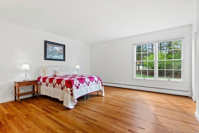 bedroom featuring wood finished floors and baseboard heating
