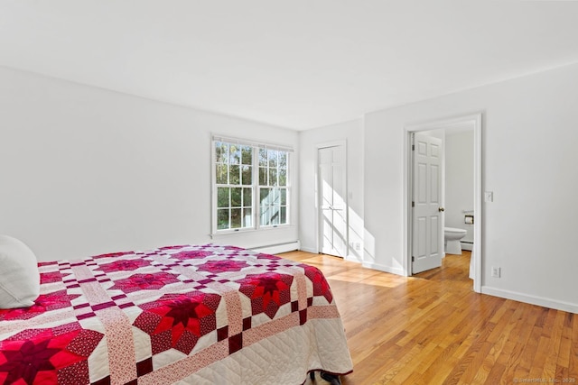 bedroom featuring light wood-style floors, baseboards, ensuite bathroom, and a baseboard heating unit
