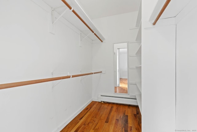 spacious closet featuring wood finished floors and a baseboard radiator