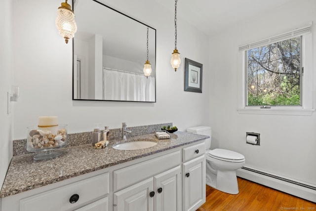 bathroom with vanity, wood finished floors, baseboard heating, and toilet