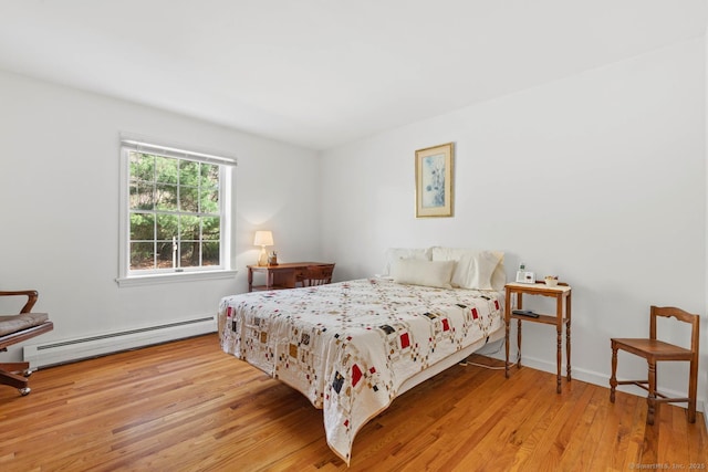 bedroom with a baseboard heating unit and wood finished floors