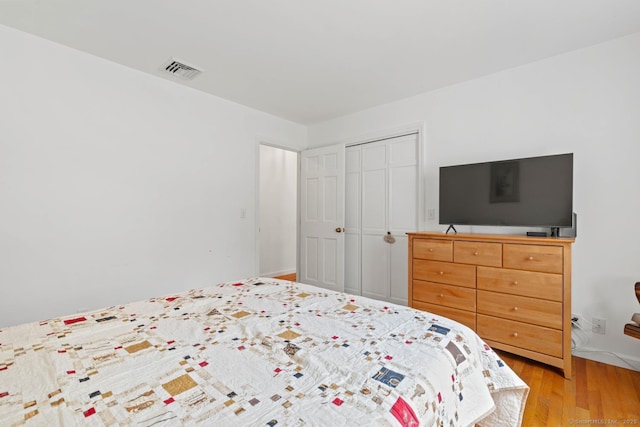 bedroom with a closet, visible vents, and light wood-type flooring