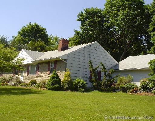 71 Schiller Rd, Fairfield, CT 06825 - view of side of home featuring a lawn, stone siding, and a chimney