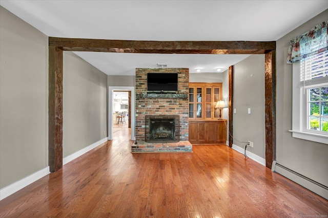 unfurnished living room featuring baseboards, light wood finished floors, a brick fireplace, and baseboard heating