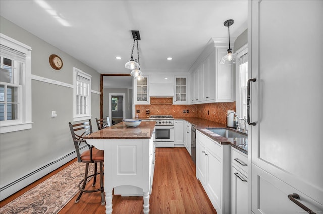 kitchen with baseboard heating, a sink, white cabinets, light wood finished floors, and stainless steel appliances