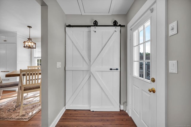 entryway featuring baseboards, dark wood finished floors, and a barn door