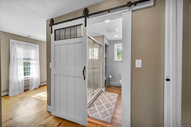 interior space featuring baseboards, a stall shower, toilet, and wood finished floors