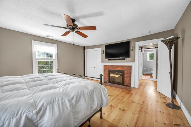 bedroom featuring light wood-type flooring, a textured ceiling, and multiple windows
