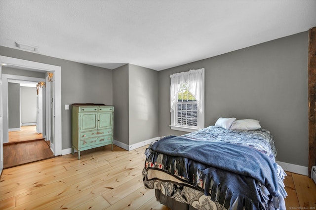 bedroom featuring baseboards, visible vents, and light wood-type flooring