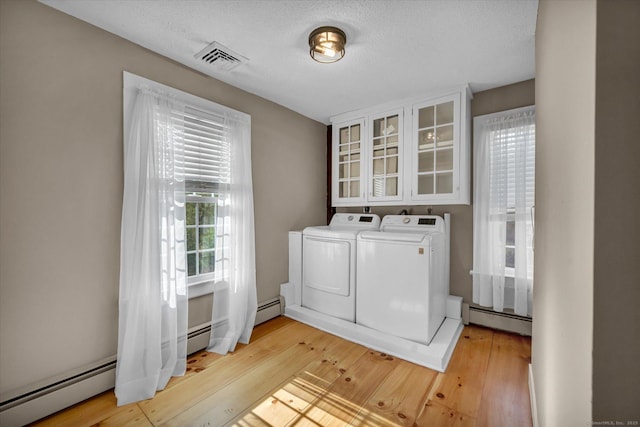clothes washing area featuring laundry area, visible vents, baseboard heating, light wood finished floors, and independent washer and dryer