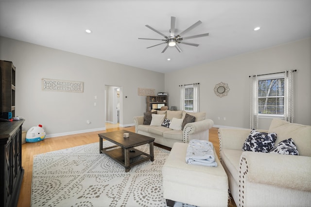 living area featuring baseboards, light wood-type flooring, a ceiling fan, and recessed lighting