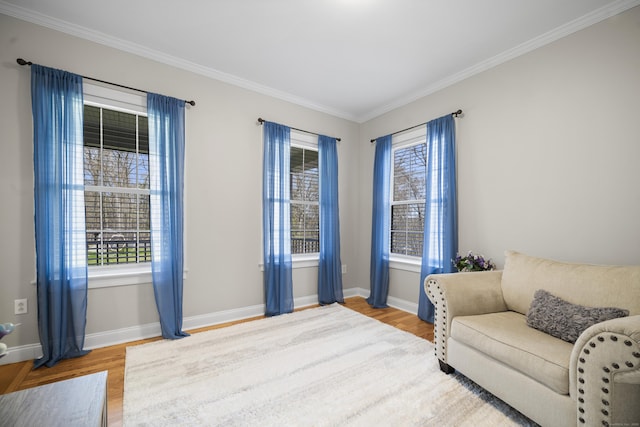sitting room featuring wood finished floors, crown molding, and baseboards
