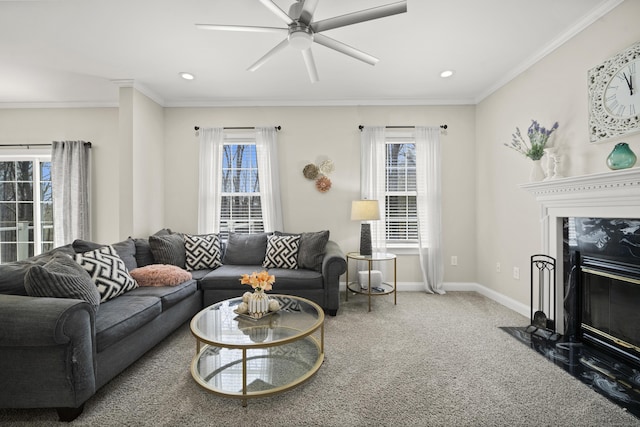 carpeted living area with a premium fireplace, ceiling fan, plenty of natural light, and ornamental molding