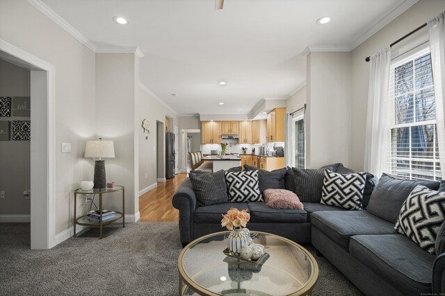 living area with ornamental molding, recessed lighting, light colored carpet, and baseboards