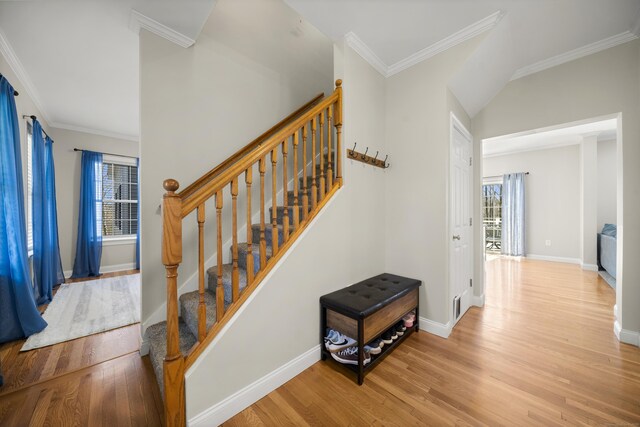 staircase featuring wood finished floors, crown molding, and baseboards