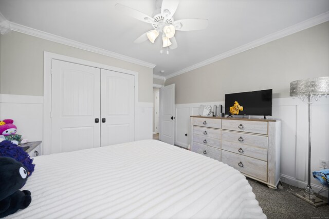 carpeted bedroom featuring ornamental molding, a closet, ceiling fan, and wainscoting